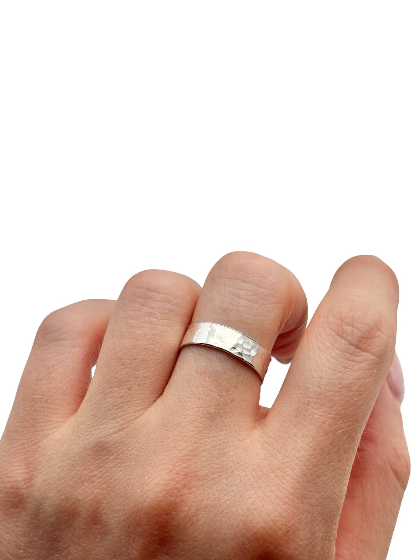 Silver hammered ring on a finger against a white background