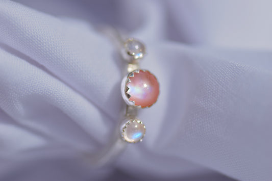 three stone silver ring featuring pink mother of pearl and two blue moonstones 
