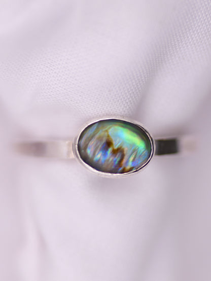 Silver ring with an oval paua shell on a white background