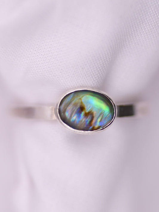 Silver ring with an oval paua shell on a white background