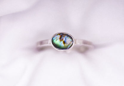 Silver ring with a paua shell gemstone on a white background