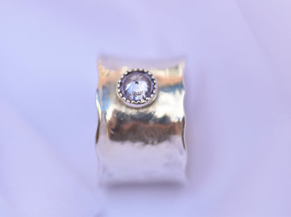 silver ring with a central gemstone on a light purple background