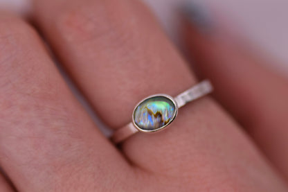 Silver ring with a paua shell gemstone on a hand