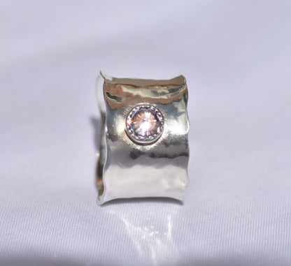 Silver ring with a central gemstone on a light gray background