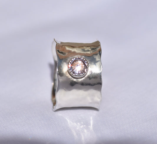 Silver ring with a central gemstone on a light gray background
