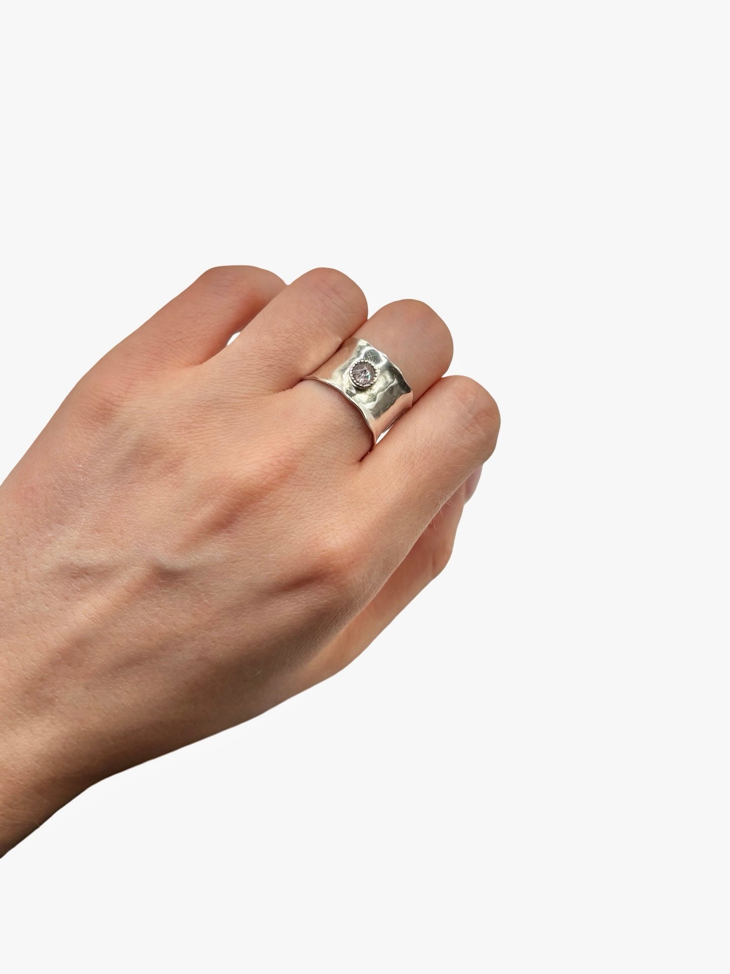 Hand wearing a silver ring with purple stone on a white background