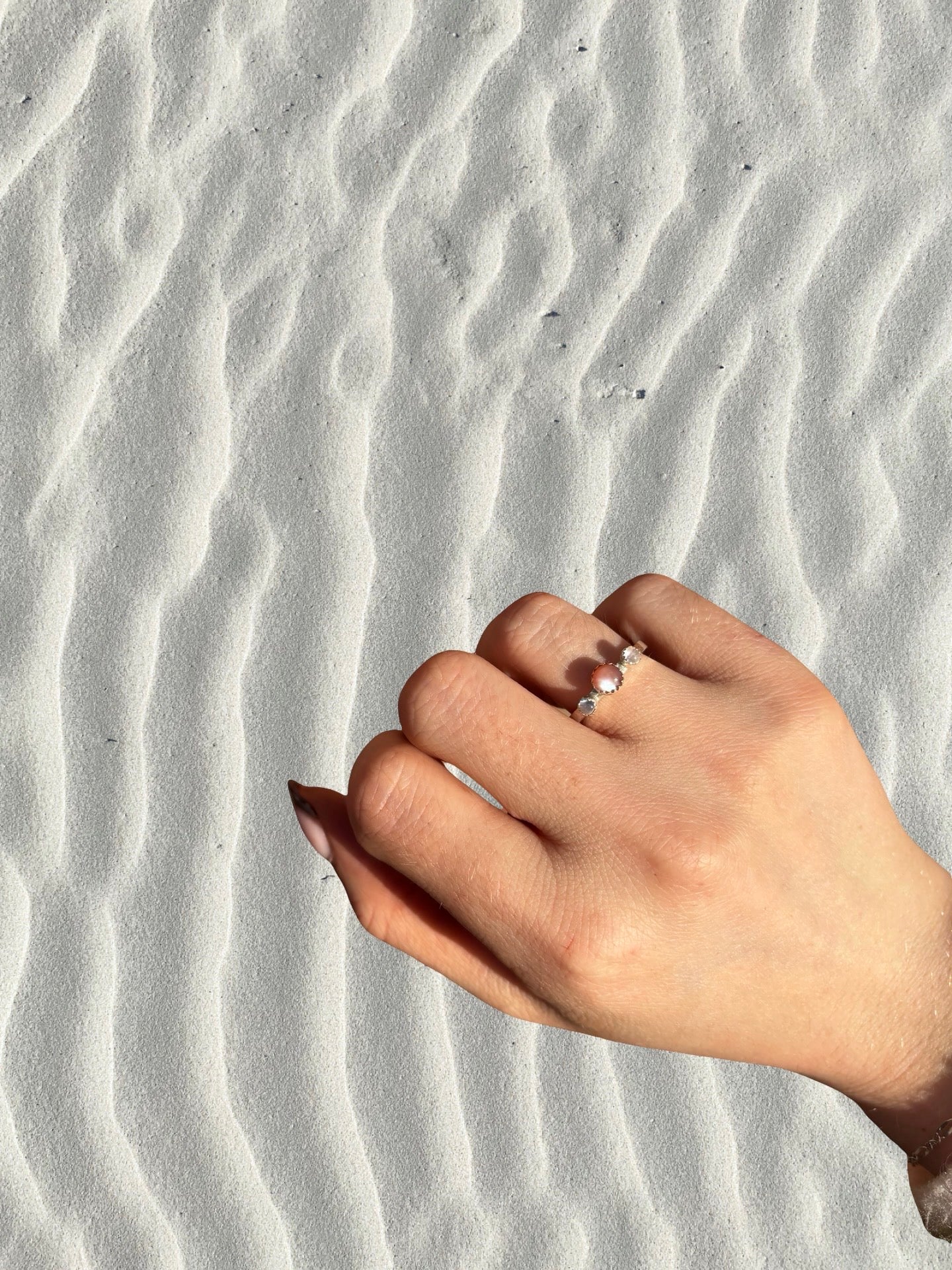 Hand with a ring on a textured sand background