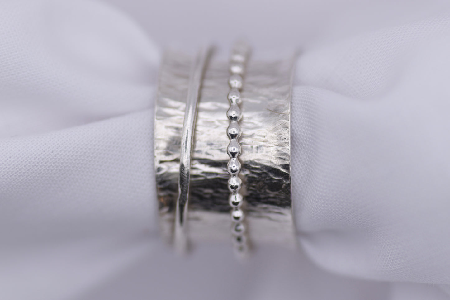  silver ripple spinning ring  on a white fabric background