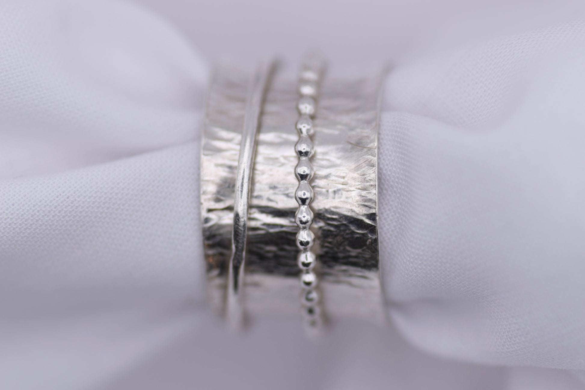  silver ripple spinning ring  on a white fabric background