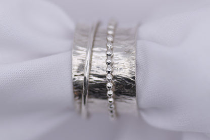  silver ripple spinning ring  on a white fabric background