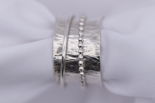  silver ripple spinning ring  on a white fabric background
