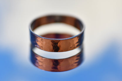 Silver hammered  ring on a reflective surface with a blurred background