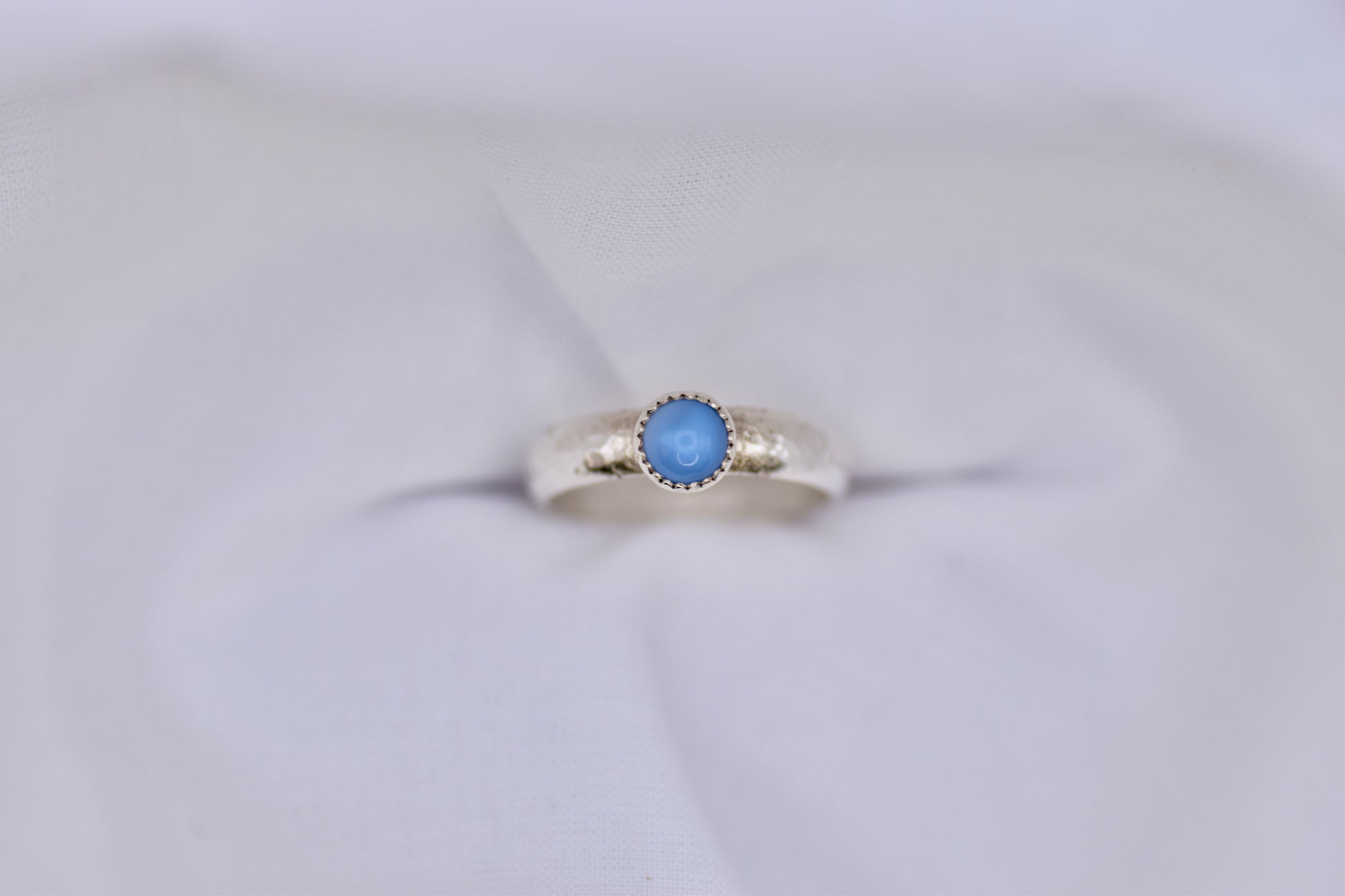 Silver ring with a blue gemstone on a light gray background