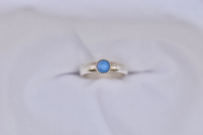 Silver ring with a blue gemstone on a light gray background