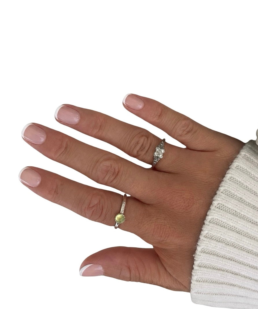 Hand wearing two rings on a white background
